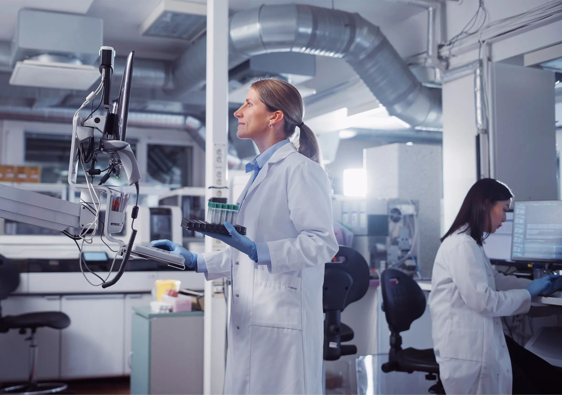 Scientist in a full white cleanroom suit working carefully with precision manufacturing or lab equipment.